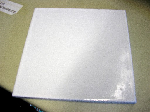 DALLE, EN PIERRE DE LAVE, TAILLEE ET EMAILLEE SUR UNE FACE, DE DIMENSION 20 CM X 20 CM X 1.5 CM.