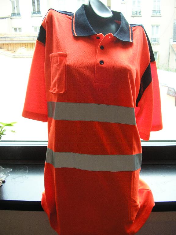VÊTEMENT POUR HOMME, GENRE POLO DE SIGNALISATION FLUORESCENT, DE HAUTE VISIBILITÉ, CONFECTIONNÉ EN ÉTOFFE DE BONNETERIE DE FIBRES SYNTHÉTIQUES (100% POLYESTER), AVEC UN COL CHEMISIER, AVEC UNE OUVERTURE PARTIELLE SE FERMANT GAUCHE SUR DROITE A L'AIDE DE TROIS BOUTONS, AVEC UNE PETITE POCHE PLAQUÉE SE FERMANT A L'AIDE D'UNE BANDE VELCRO ET PLACÉE AU NIVEAU DE LA POITRINE DROITE, ET DES MANCHES COURTES DONT LES EXTRÉMITÉS SE TERMINENT PAR UN OURLET. SUR LE DEVANT ET A L'ARRIÈRE, L'ARTICLE PRÉSENTE DEUX BANDES HORIZONTALES RÉTRORÉFLÉCHISSANTES ET ARGENTÉES DE CINQ CENTIMÈTRES DE LARGE ET COUSUES SOUS LA POITRINE ET AU NIVEAU DE LA TAILLE. EN OUTRE, LA BASE DU VÊTEMENT EST OURLÉE.