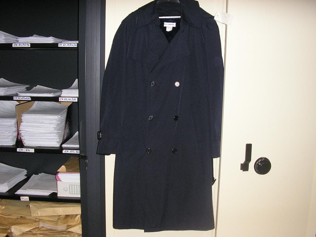 VÊTEMENT POUR HOMME DE TYPE IMPERMÉABLE, CONFECTIONNÉ EN TISSU DE FIBRES SYNTHÉTIQUES MAJORITAIRES(65% POLYESTER,35% COTON) DESCENDANT AU DESSOUS DU GENOU, AVEC UNE OUVERTURE COMPLÈTE SUR LE DEVANT SE FERMANT GAUCHE SUR DROITE AU MOYEN DE BOUTONS,AVEC UN BAVOLET FIXÉ PAR UN BOUTON,AVEC DES MANCHES LONGUES TERMINÉES PAR UNE PATTE DOTÉE D'UNE BOUCLE ET COULISSANT DANS TROIS PASSANTS,AVEC DEUX POCHES SUR LE DEVANT,AVEC DES PATTES D'ÉPAULES,AVEC UNE CEINTURE A BOUCLE MAINTENUE A LA TAILLE PAR DEUX PASSANTS,AVEC ÉGALEMENT UNE BASE OURLÉE.
DANS LE DOS, IL POSSÈDE UNE CAPUCHE AMOVIBLE FIXÉE SUR LE PIED DE COL PAR CINQ BOUTONS,UN DEUXIÈME BAVOLET AINSI QU'UNE FENTE PARTANT DU MILIEU DU DOS.
LE VÊTEMENT POSSÈDE UNE DOUBLURE INTÉRIEURE AMOVIBLE EN FAUSSE FOURRURE QUI EST FIXEE A L IMPERMÉABLE AU MOYEN D'UNE FERMETURE A GLISSIÈRE. 

POIDS: ENVIRON 1.300 KILOGRAMMES