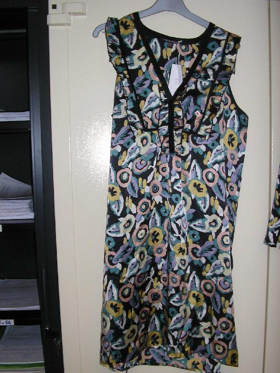 ROBE,DE FACTURE AMPLE ET LÉGÈRE,CONFECTIONNÉE EN TISSU DE SOIE,DESCENDANT AU DESSUS DU GENOU,AVEC UNE ENCOLURE DÉCOLLETÉE POURVUE D'UNE OUVERTURE PARTIELLE SE FERMANT DROITE SUR GAUCHE AU MOYEN D'UN SYSTÈME DE BOUTONNAGE,AVEC DES BRETELLES SE PROLONGEANT PAR UN VOLANT PLISSÉ DONT LES BORDS SONT SURFILÉS,AVEC UNE CEINTURE A NOUER AU NIVEAU DES HANCHES MAINTENUE PAR UN LIEN DE CHAQUE CÔTÉ,AVEC UN LÉGER OURLET A LA BASE DU VÊTEMENT.LA ROBE COMPORTE UN BIAIS DE COULEUR NOIRE AU NIVEAU DE L'ENCOLURE SE PROLONGEANT SUR TOUTE LA LONGUEUR DE L'OUVERTURE PARTIELLE,AINSI QUE DE LÉGÈRES FRONCES DANS LE DOS.

TAILLE 40
LONGUEUR:94 CM
