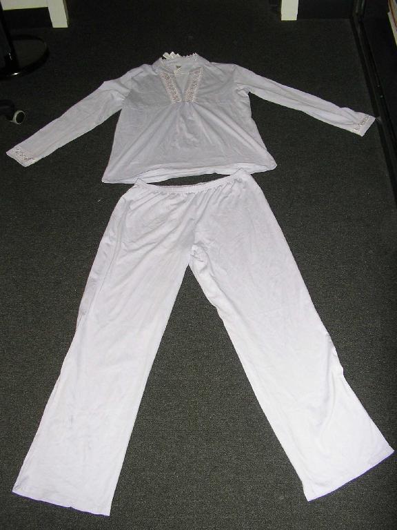 PYJAMA POUR FEMME CONFECTIONNÉ EN BONNETERIE DE COTON COMPOSÉ:
- D'UN HAUT,DE COULEUR UNIE,DESCENDANT SUR LES HANCHES AVEC UN COL MAO,AVEC UNE ENCOLURE EN V ORNÉE DE CHAQUE CÔTÉ D'UNE BANDE DE GUIPURE,AVEC DES MANCHES LONGUES TERMINÉES PAR OURLET ET COMPORTANT ÉGALEMENT DES GUIPURES AU NIVEAU DES POIGNETS,AVEC UN OURLET A LA BASE DU VÊTEMENT.DES FRONCES DÉCORATIVES SONT PRÉSENTES SUR LE DEVANT AU NIVEAU DE LA DÉCOUPE POITRINE. 
- D'UN PANTALON,DE COULEUR IDENTIQUE AU VÊTEMENT RECOUVRANT LE HAUT DU CORPS,DESCENDANT JUSQU'AUX CHEVILLES, SANS SYSTÈME D'OUVERTURE SUR LE DEVANT,AVEC UNE TAILLE LÉGÈREMENT ÉLASTIQUÉE, AVEC UN OURLET A LA BASE DES JAMBES. 

TAILLE 38/40