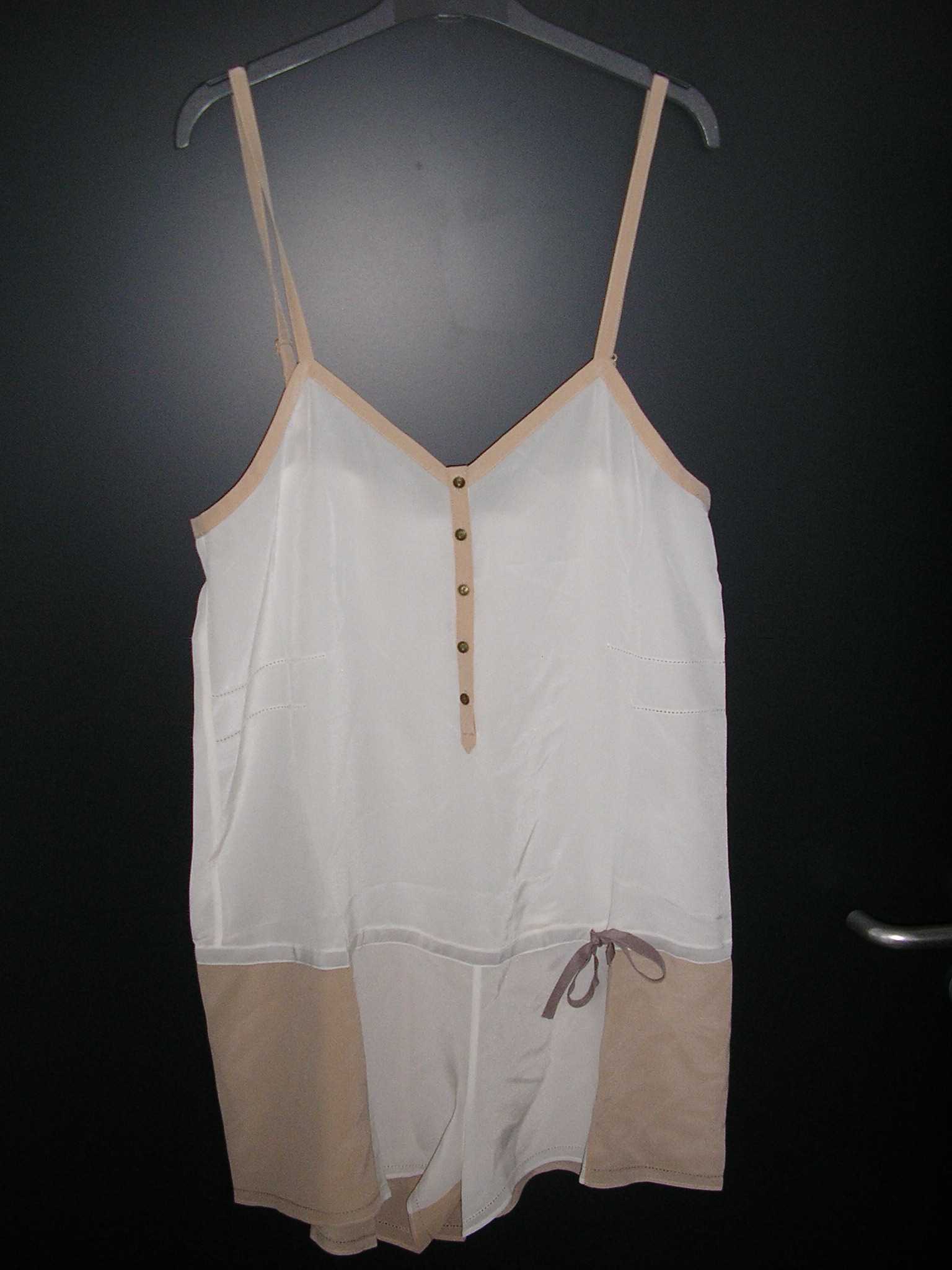 TENUE D'INTÉRIEUR POUR FEMMES, TYPE COMBISHORT, CONFECTIONNÉ EN TISSU DE SOIE, RECOUVRANT A LA FOIS LA PARTIE SUPÉRIEURE ET INFÉRIEURE DU CORPS JUSQU'AU HAUT DES CUISSES, ENVELOPPANT SÉPARÉMENT CHAQUE JAMBE. IL COMPORTE DE FINES BRETELLES RÉGLABLES, UNE ENCOLURE EN "V" PROLONGÉE PAR UNE OUVERTURE PARTIELLE SE FERMANT DROITE SUR GAUCHE AU MOYEN DE PETITS BOUTONS, ET UN LIEN SOUS TUNNEL RESSERRANT AU NIVEAU DE LA TAILLE A NOUER SUR LE CÔTÉ GAUCHE. LA BASE DU COMBISHORT EST OURLÉE.
