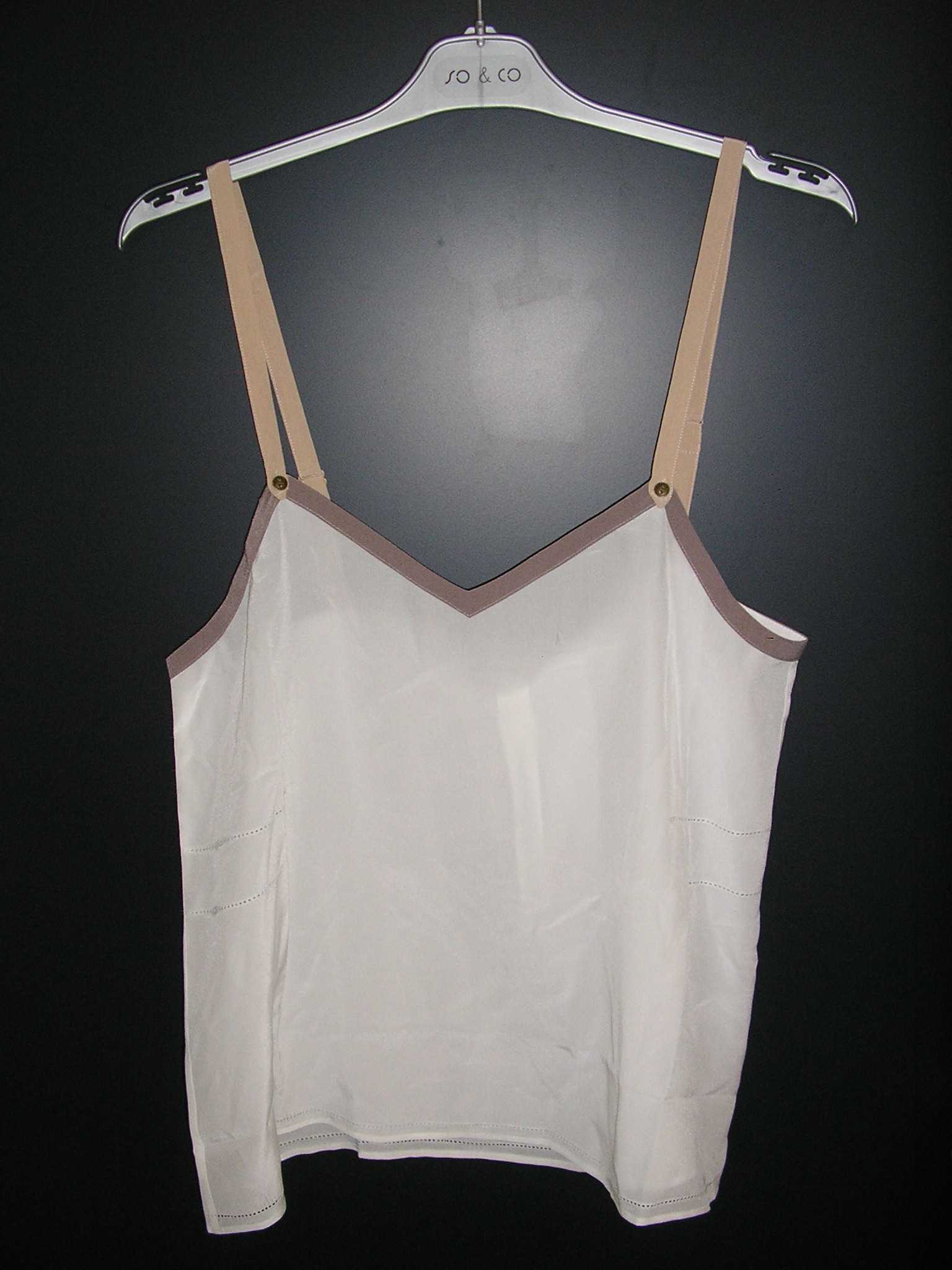 VÊTEMENT GENRE BLOUSE-CARACO, CONFECTIONNÉ EN TISSU DE SOIE, DE FACTURE AMPLE ET FLUIDE, DESTINÉ A COUVRIR LA PARTIE SUPÉRIEURE DU CORPS ET DESCENDANT JUSQU’AUX HANCHES, SANS OUVERTURE, AVEC DEUX FINES BRETELLES RÉGLABLES PRÉSENTANT UNE PETIT BOUTON SUR LE DEVANT, AVEC UNE ENCOLURE EN « V » POURVUE D'UN BIAIS SUR TOUT LE POURTOUR ET AVEC UN OURLET A LA BASE DU VÊTEMENT.