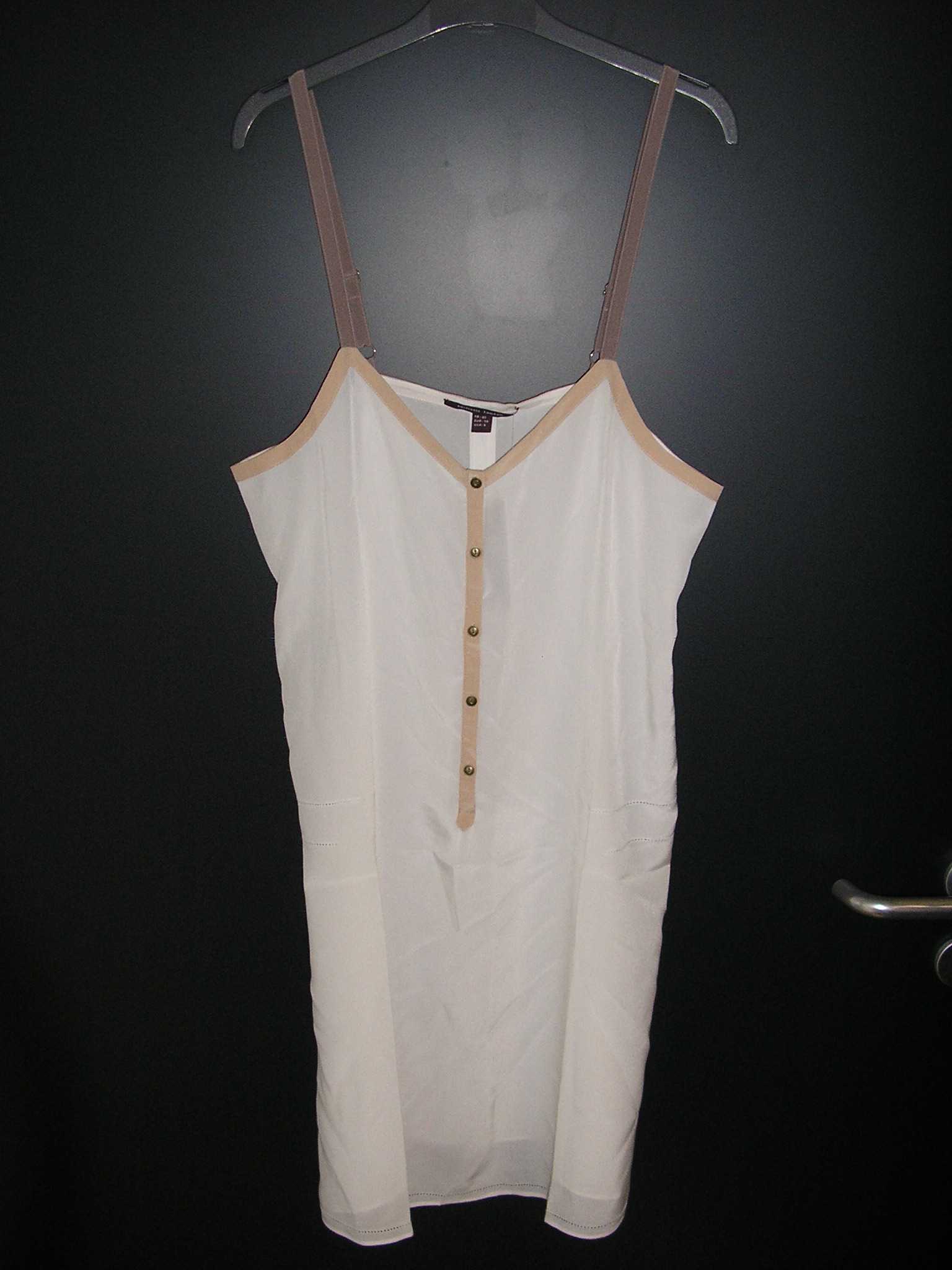 COMBINAISON POUR FEMMES, GENRE FOND DE ROBE, CONFECTIONNÉ EN TISSU DE SOIE, DE FACTURE LÈGÈRE, DESCENDANT JUSQU'À MI-CUISSE, AVEC UN DÉCOLLETÉ EN "V" BORDÉ PAR UN BIAIS SUR TOUT LE POURTOUR, AVEC UNE OUVERTURE PARTIELLE SUR LE DEVANT SE FERMANT DROITE SUR GAUCHE AU MOYEN DE PETITS BOUTONS, AVEC DE FINES BRETELLES RÉGLABLES, ET UN OURLET A LA BASE DU VÊTEMENT.

LONGUEUR : ENVIRON 92 CM