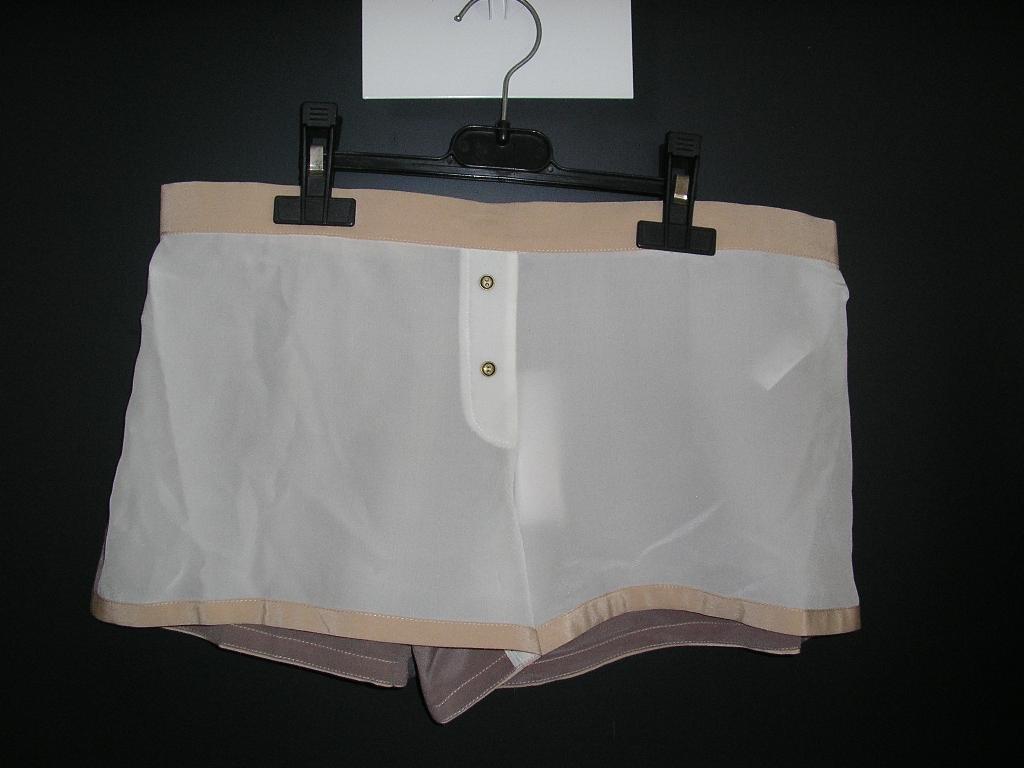 PETIT SHORT D'INTÉRIEUR CONFECTIONNÉ EN TISSU DE SOIE, DE FACTURE LÉGÈRE ET FLUIDE, SANS DOUBLURE ET SANS OUVERTURE, AVEC UNE BANDE ÉLASTIQUÉE DANS LE DOS ET DEUX PETITS BOUTONS DÉCORATIFS SUR LE DEVANT. LA BASE DU SHORT ET LE POURTOUR DE LA TAILLE PRÉSENTENT UN BIAIS.