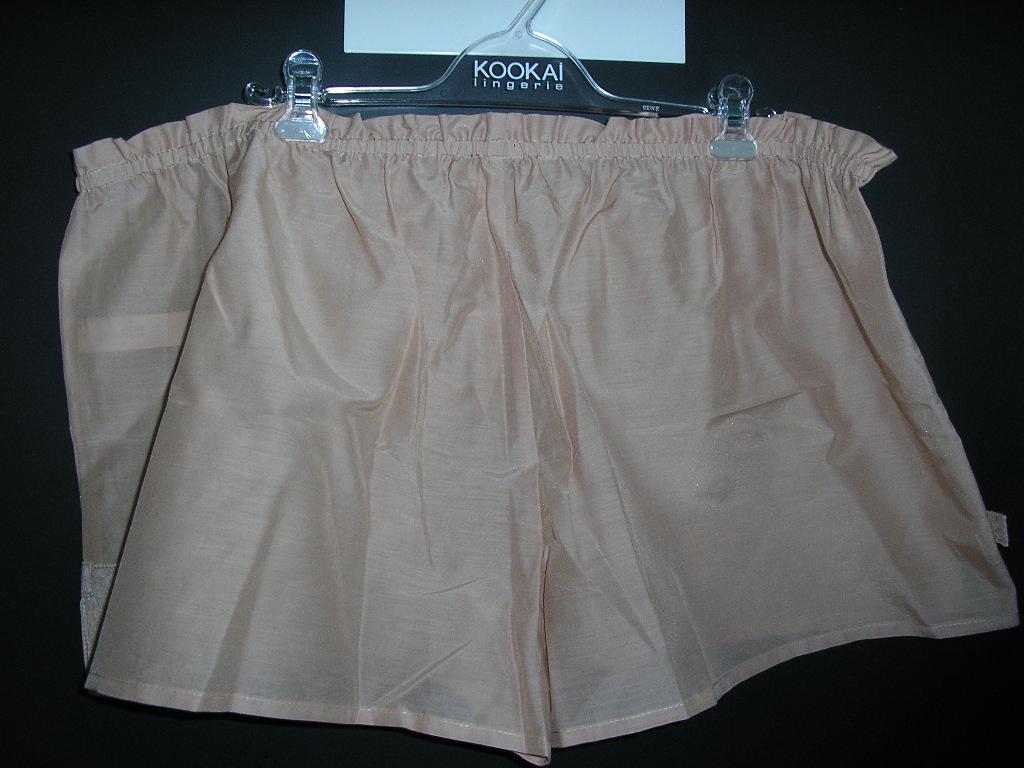PETIT SHORT D'INTÉRIEUR CONFECTIONNÉ MAJORITAIREMENT EN TISSU DE COTON (75% COTON, 25% SOIE), DE FACTURE LÉGÈRE, UNICOLORE, SANS DOUBLURE, SANS OUVERTURE SUR LE DEVANT ET COMPORTANT UNE BANDE ÉLASTIQUÉE A LA TAILLE. LA BASE DU SHORT EST OURLÉE ET PRÉSENTE DEUX FENTES LATÉRALES BORDÉES DE GALONS, ASPECT DENTELLE.
