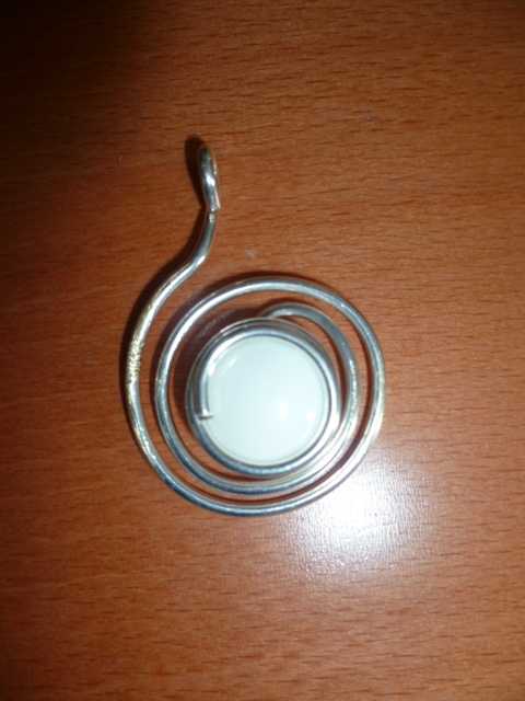 PENDENTIF SE PRÉSENTANT SOUS LA FORME D'UNE SPIRALE EN LAITON (METAL COMMUN)RECOUVERTE D'UNE FINE COUCHE D'ARGENT AVEC EN SON CENTRE UN GALET EN VERRE. 

DIAMETRE: 3.5 CM