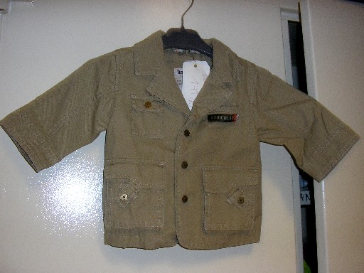 VETEMENT DESTINE A RECOUVRIR LA PARTIE SUPERIEURE DU CORPS, GENRE VESTE, POUR GARCONS, EN TISSU 100% COTON, NON DOUBLE, COMPORTANT UN COL TAILLEUR, UNE OUVERTURE COMPLETE SUR LE DEVANT AVEC DES BOUTONS SE FERMANT DE GAUCHE SUR DROITE, DES MANCHES LONGUES AUX EXTREMITES OURLEES, UNE POCHE DE CHAQUE COTE DE LA POITRINE DONT CELLE DU COTE DROIT AVEC RABAT ET BOUTON-PRESSION, UNE POCHE A SOUFFLET AVEC RABAT ET BOUTON-PRESSION DE CHAQUE COTE DU VETEMENT, UNE FENTE D'AISANCE AU BAS DU DOS, LA BASE EST OURLEE, LOGO PUBLICITAIRE COUSU SUR LA POITRINE, IMPRIME AVEC DES INSCRIPTIONS ET DES BRODERIES DANS LE DOS.
