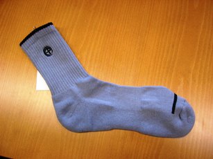 CHAUSSETTE POUR ADULTES CONFECTIONNEE EN ETOFFE DE BONNETERIE MAJORITAIREMENT DE FIBRES ARTIFICIELLES (85% BAMBOU, 15% SPANDEX) DE COULEUR UNIE, AVEC UN LISERET D'UNE AUTRE COULEUR A CHAQUE EXTREMITE, AVEC DES LETTRES BRODEES DANS UN CERCLE VERS LE HAUT DE LA CHAUSSETTE. LE DESSOUS DU PIED EST RENFORCE DU TALON A LA POINTE POUR LIMITER LA TRANSPIRATION.