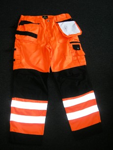 VETEMENT DE TRAVAIL, GENRE PANTALON, EN TISSU DE COTON MAJORITAIRE (60% COTON, 40% POLYESTER), FLUORESCENT, BICOLORE, POUR HOMMES, DESCENDANT JUSQU'AUX CHEVILLES EN ENVELOPPANT SÉPARÉMENT CHAQUE JAMBE,  AVEC DES COUTURES SAFETY, AVEC UNE OUVERTURE PARTIELLE SUR LE DEVANT FERMANT GAUCHE SUR DROITE PAR FERMETURE A GLISSIERE,  RABAT ET BOUTON, AVEC DIFFERENTS TYPES DE POCHES AU NIVEAU DES HANCHES ET DES JAMBES SUR LE DEVANT : POCHES AMOVIBLES, POCHES PLAQUEES, POCHES AVEC FERMETURE A GLISSIERE, POCHES A RABAT ET BOUTON PRESSION OU BANDE VELCRO, AVEC UNE BANDE DE TISSU COUSUE AU NIVEAU DES GENOUX FAISANT LE TOUR DE LA JAMBE ET A LA BASE, AVEC DEUX BANDES REFLECHISSANTES COUSUES SUR CHAQUE JAMBE, AVEC DEUX POCHES PLAQUEES ET UNE POCHE VOLANTE AU DOS, AVEC TROIS PASSANTS COUSUS SUR LE COTE DROIT ET UN A GAUCHE. LA BASE EST OURLEE.