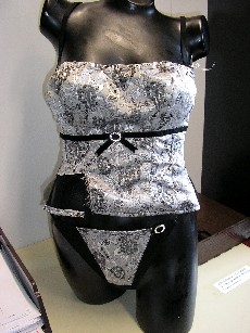 ENSEMBLE DE DEUX VETEMENTS ASSORTIS, CONFECTIONNES EN TISSU 100% POLYAMIDE, AVEC DOUBLURE ASPECT VOILE, COMPOSE:

-D'UN VETEMENT DESTINE A RECOUVRIR LE HAUT DU CORPS, GENRE BUSTIER, COMPORTANT UNE ENCOLURE DROITE, UNE DECOUPE POITRINE, DE FINES BRETELLES REGLABLES, UNE OUVERTURE DANS LE DOS AVEC POUR FERMETURE DES AGRAFES EN METAL, DES BALEINES SOUPLES EN MATIERE PLASTIQUE SUR LES COTES ET DANS LE DOS POUR ASSURER LE MAINTIEN, LA BASE DU VETEMENT SE TERMINE PAR UN OURLET, AVEC POUR DECORATION UNE PARTIE ASPECT VOILE DE CHAQUE COTE DANS LE DOS, UN GALON SOUS LA POITRINE ET UNE BROCHE EN STRASS SOUS LA POITRINE AU MILIEU.

-D'UN STRING, EN FORME DE TRIANGLE, COMPORTANT UN ELASTIQUE POUR LE MAINTIEN, L'ENTREJAMBE EST DOUBLE, LES BORDURES DU VETEMENT SONT ELASTIQUEES, AVEC POUR DECORATION UNE BROCHE EN STRASS SUR LE HAUT DU COTE GAUCHE.