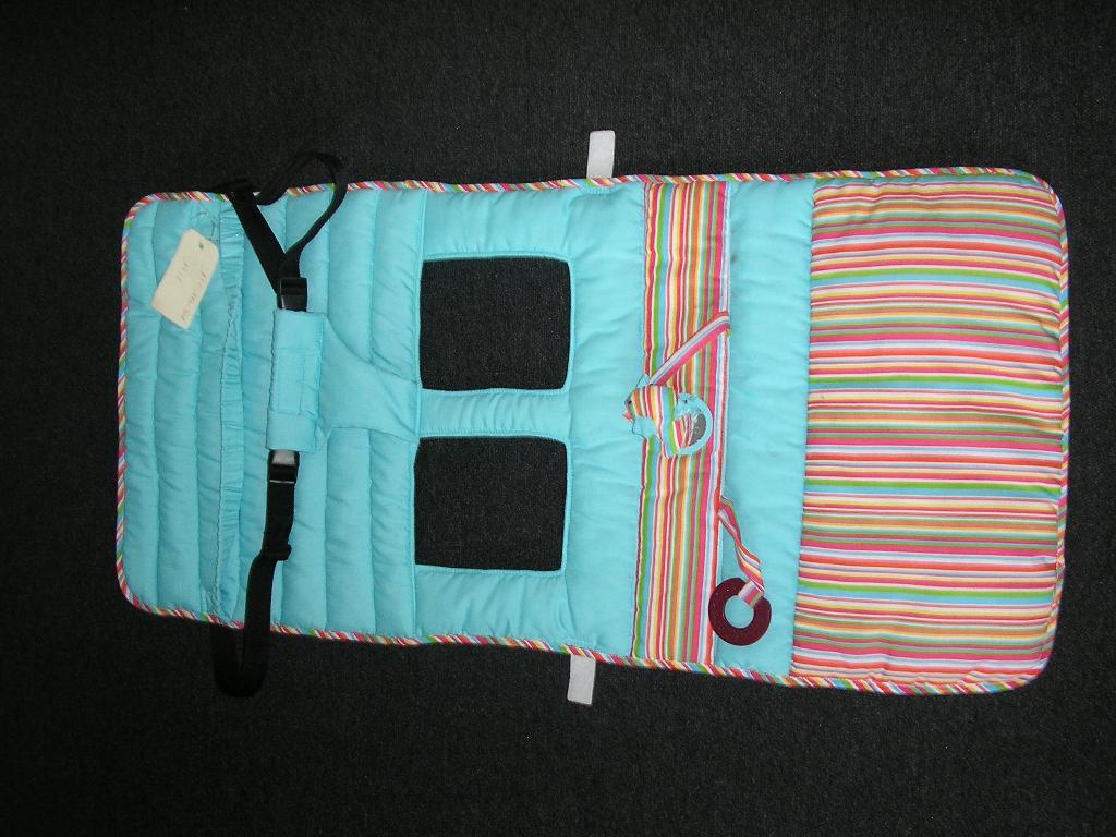 ARTICLE TEXTILE DE FORME RECTANGULAIRE (94 X 58 CM), CONFECTIONNE EN MATIERE TEXTILE MATELASSEE AVEC SURFACE EXTERIEURE EN TISSU DE COTON(100% COTON). 
CET ARTICLE CONSTITUE UNE PROTECTION MATELASSEE A PLACER SUR LE SIEGE ENFANT DES CADDIES DE SUPERMARCHE. IL PRESENTE UN OURLET EN TISSU BARIOLE SUR TOUT SON POURTOUR, DEUX BANDES DE CE MEME TISSU BARIOLE SUR LA FACE AVANT ET DEUX TROUS POUR PASSER LES JAMBES. UN PETIT MIROIR EST COUSU AU CENTRE DE L'ARTICLE, AINSI QU'UN PETIT OISEAU EN TEXTILE REMBOURRE ET UN ANNEAU DENTAIRE EN PLASTIQUE FIXES A L'ARTICLE PAR UNE PATTE DE TISSU. L'ARTICLE PRESENTE UNE SANGLE EN TISSU ELASTIQUEE PERMETTANT DE LE MAINTENIR SUR LE SIEGE DU CADDIE, DEUX BANDES VELCRO ET UNE SANGLE EN TISSU SE FERMANT AVEC DES CLIPS PERMETTANT DE MAINTENIR L'ENFANT SUR LE SIEGE.