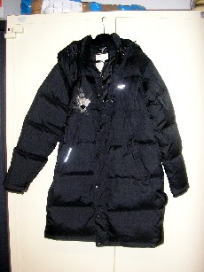 VETEMENT DESTINE A RECOUVRIR LE CORPS, GENRE MANTEAU, POUR HOMMES, CONFECTIONNE EN TISSU 100% POLYESTER AVEC UNE ENDUCTION DE MATIERE PLASTIQUE SUR LA FACE INTERIEURE VISIBLE A L'OEIL NU, IL COMPORTE UN COL MONTANT, UN CAPUCHON AMOVIBLE PAR FERMETURE A GLISSIERE AVEC DES LIENS A NOUER, UNE OUVERTURE COMPLETE SUR LE DEVANT AU MILIEU AVEC UNE FERMETURE A GLISSIERE ET UNE PATTE DE PROTECTION AVEC DES BOUTONS-PRESSIONS SE FERMANT DE GAUCHE SUR DROITE, DES MANCHES LONGUES AUX EXTREMITES OURLEES ET DOUBLEES D'UN POIGNET EN BORD COTE, UNE POCHE EN BIAIS AVEC UN BOUTON-PRESSION DE CHAQUE COTE DU VETEMENT, LA BASE SE TERMINE PAR UN OURLET, ENTIEREMENT REMBOURRE 50% PLUME ET 50% DUVET, AVEC UNE DOUBLURE COMPLETE ET UNE POCHE INTERIEURE A FERMETURE PAR BANDE VELCRO, LOGO PUBLICITAIRE IMPRIME SUR LA POITRINE COTE GAUCHE.