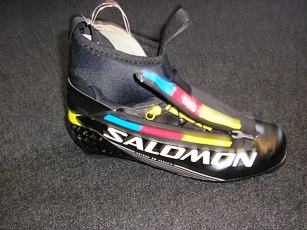 CHAUSSURE POUR LA PRATIQUE DU SKI DE FOND, NON RECONNAISSABLE COMME ETANT POUR HOMME OU POUR FEMME, COUVRANT LA CHEVILLE, AVEC UN DESSUS EN MATIERE PLASTIQUE, AVEC UNE SEMELLE EXTERIEURE EN MATIERE PLASTIQUE, AVEC UNE OUVERTURE SUR LE COTE EXTERIEURE MUNIE D'UNE FERMETURE A GLISSIERE, AVEC UN CHAUSSON INTERIEUR EN ETOFFE DE BONNETERIE REMBOURREE, AVEC UNE LANGUETTE RIGIDE EN MATIERE PLASTIQUE, AVEC DES CROCHETS DE CHAQUE COTE DE LA CHAUSSURE PERMETTANT UNE FERMETURE PAR LACAGE, AVEC UNE LANIERE AU DOS ET SUR LE DEVANT DE LA CHAUSSURE,  LA SEMELLE EXTERIEURE COMPORTE UN SYSTEME D'ATTACHES AVEC DEUX BARRES EN METAL. CETTE CHAUSSURE COMPORTE LA MARQUE SUR LES COTES.