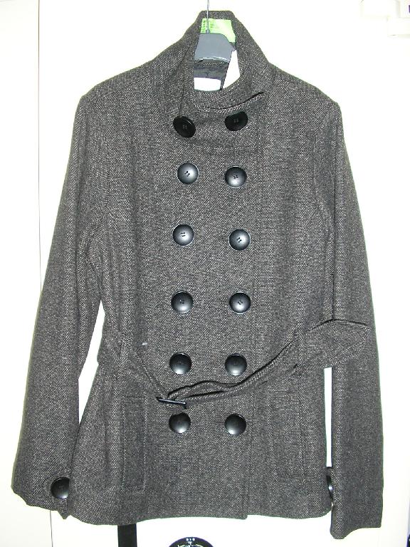 VESTE 3/4 POUR FEMMES, EN TISSU MAJORITAIRE DE FIBRES SYNTHÉTIQUES (55% POLYESTER, 45% LAINE), DESTINÉE À RECOUVRIR LA PARTIE SUPÉRIEURE DU CORPS, DE FORME DROITE, DESCENDANT SOUS LES HANCHES, CONSTITUÉE DE DEUX PANNEAUX FRONTAUX ET D'UN PANNEAU DORSAL COUSUS ENSEMBLE DANS LE SENS DE LA LONGUEUR, AVEC DEUX POCHES SUR LE DEVANT, AVEC UN COL MONTANT ET DES MANCHES LONGUES DONT L'EXTRÉMITÉ PRÉSENTE UN BOUTON DÉCORATIF. LA VESTE S'OUVRE COMPLÈTEMENT SUR LE DEVANT ET SE FERME DROITE SUR GAUCHE AU MOYEN DE DEUX RANGÉES DE BOUTONS. EN OUTRE, LA VESTE PRÉSENTE UNE CEINTURE A LA TAILLE, MAINTENUE PAR 4 PASSANTS ET SE FERMANT A L'AIDE D'UNE BOUCLE EN PLASTIQUE.