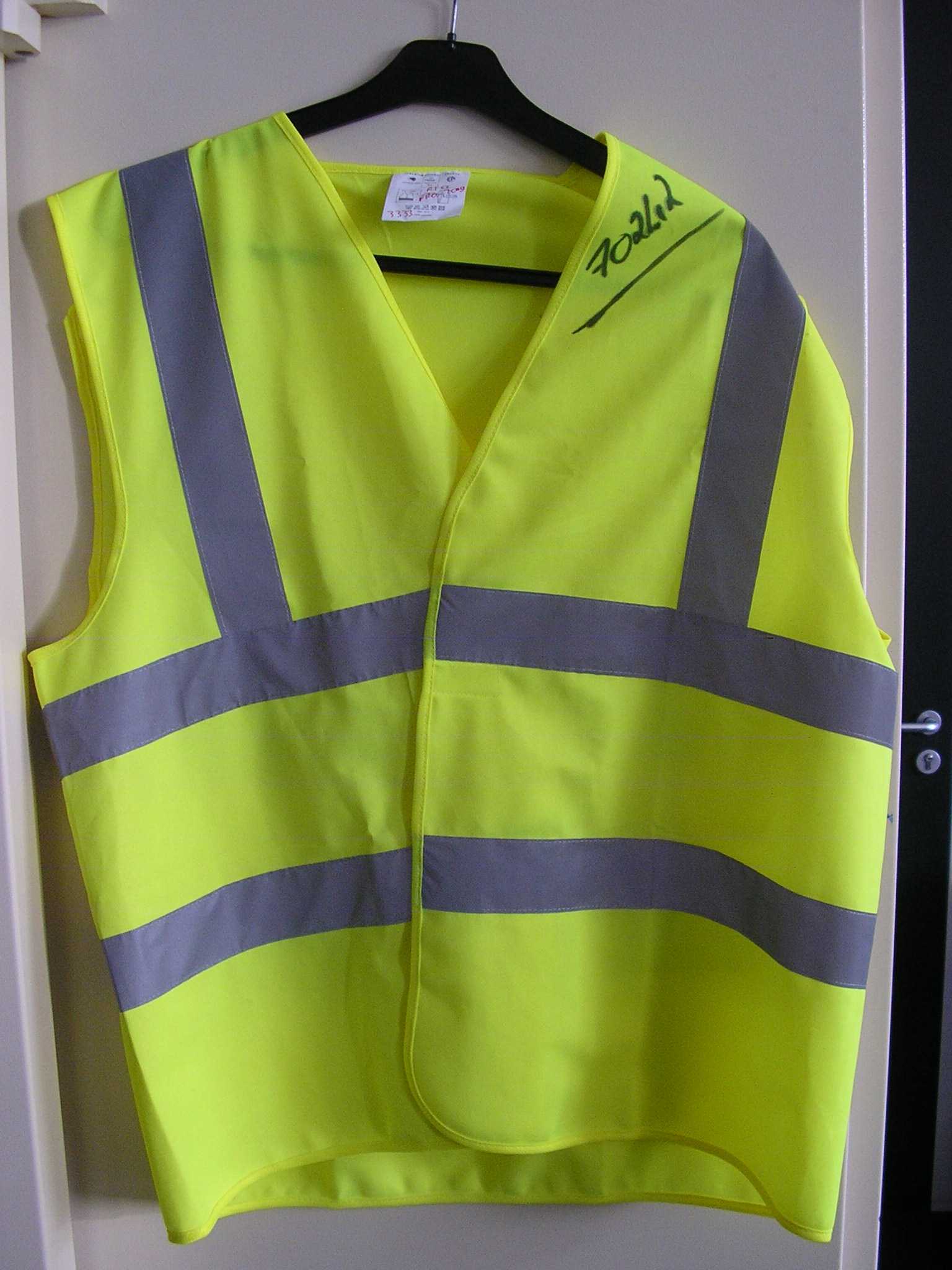 AUTRE VÊTEMENT DE SIGNALISATION FLUORESCENT POUR HOMME, GENRE GILET SANS MANCHE, CONFECTIONNÉ EN TISSU DE FIBRES SYNTHÉTIQUES (100% POLYESTER), AVEC UNE OUVERTURE COMPLÈTE SUR LE DEVANT SE FERMANT GAUCHE SUR DROITE A L'AIDE D'UNE BANDE VELCRO, AVEC UN COL EN V, AVEC UN BIAIS A LA BASE, SUR LE DEVANT ET AUX ECHANCRURES DES MANCHES.
SUR LE DEVANT ET DANS LE DOS DU VÊTEMENT, SONT COUSUES DEUX BANDES VERTICALES ET DEUX BANDES HORIZONTALES RÉTRORÉFLÉCHISSANTES ET ARGENTÉES DE CINQ CENTIMÈTRES DE LARGE.