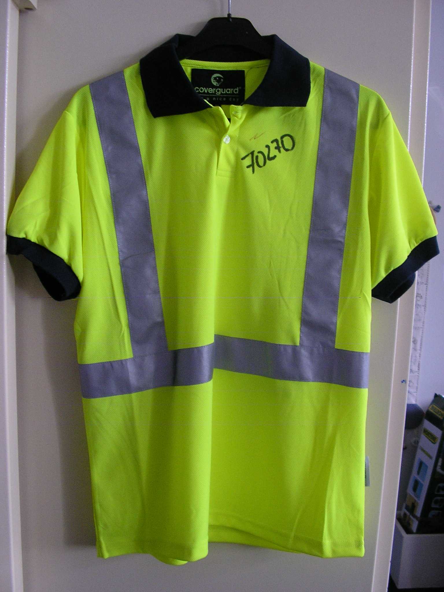 VÊTEMENT POUR HOMME, GENRE POLO DE SIGNALISATION FLUORESCENT, DE HAUTE VISIBILITÉ, CONFECTIONNÉ EN ÉTOFFE DE BONNETERIE DE FIBRES SYNTHÉTIQUES (100% POLYESTER), AVEC UN COL CHEMISIER, AVEC UNE OUVERTURE PARTIELLE SOUS L'ENCOLURE SE FERMANT GAUCHE SUR DROITE A L'AIDE DE BOUTONS, AVEC UN OURLET A LA BASE ET DES MANCHES COURTES DONT LES EXTRÉMITÉS SE TERMINENT PAR UN BORD-COTE.
SUR LE DEVANT ET DANS LE DOS DU VÊTEMENT, SONT COUSUES DEUX BANDES VERTICALES ET UNE BANDE HORIZONTALE RÉTRORÉFLÉCHISSANTES ET ARGENTÉES DE CINQ CENTIMÈTRES DE LARGE.