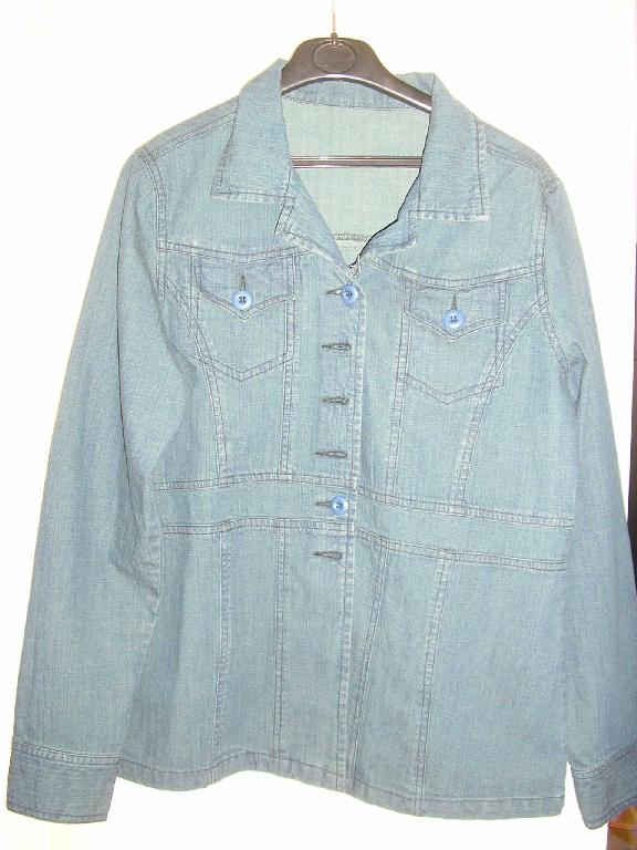 VESTE POUR FEMME CONFECTIONNÉE EN TISSU DE COTON DE TYPE "DENIM", CONSTITUÉE DE DEUX PANNEAUX FRONTAUX ET D'UN PANNEAU DORSAL, DESCENDANT SUR LES HANCHES, SANS DOUBLURE, AVEC UNE OUVERTURE COMPLÈTE SUR LE DEVANT SE FERMANT DROITE SUR GAUCHE AU MOYEN DE BOUTONS, AVEC UN COL TAILLEUR, AVEC DES MANCHES LONGUES DONT L'EXTRÉMITÉ MUNIE D'UNE FENTE SE FERME AU MOYEN D'UN BOUTON AU NIVEAU DU POIGNET, ET DEUX PETITES POCHES POITRINE À RABAT SE FERMANT A L'AIDE D'UN BOUTON. LA BASE DU VÊTEMENT EST OURLÉE.