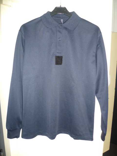 VÊTEMENT POUR HOMMES, GENRE POLO, DESTINÉ A RECOUVRIR LA PARTIE SUPÉRIEURE DU CORPS, EN BONNETERIE DE FIBRES SYNTHÉTIQUES (POLYESTER). IL COMPORTE UN COL CHEMISIER, UNE OUVERTURE PARTIELLE SOUS L'ENCOLURE SE FERMANT GAUCHE SUR DROITE AU MOYEN DE DEUX BOUTONS, DES MANCHES LONGUES DONT L'EXTRÉMITÉ SE TERMINE PAR UN BORD-CÔTE, UN ATTACHE-ÉCUSSON CARRÉ EN VELCRO AU MILIEU DE LA POITRINE ET UN OURLET A LA BASE DU VÊTEMENT.