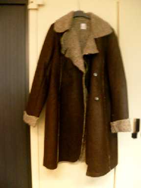 VETEMENT DESTINE A COUVRIR LE HAUT DU CORPS, GENRE MANTEAU, DESCENDANT JUSQU'AUX GENOUX, COMPOSE DE 6 PANNEAUX COUSUS ENSEMBLE DANS LE SENS DE LA LONGUEUR, CONFECTIONNE EN ETOFFE DE BONNETERIE DE FIBRES SYNTHETIQUES (POLYESTER) IMITATION PEAU CONTRECOLLEE A UNE AUTRE ETOFFE DE BONNETERIE IMITATION LAINE DE MOUTON. 
L'ARTICLE POSSEDE UN COL A RABAT, UNE OUVERTURE COMPLETE SE FERMANT DROITE SUR GAUCHE A L'AIDE DE BOUTONS-PRESSION ET DES MANCHES LONGUES RABATTUES A LEURS EXTREMITES.  
LONGUEUR EN CM : 96.