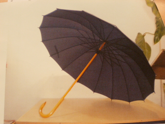 PARAPLUIE EN TISSU IMPRIME, À MANCHE FIXE ET POIGNÉE EN BOIS, AVEC BALEINES METALLIQUES.