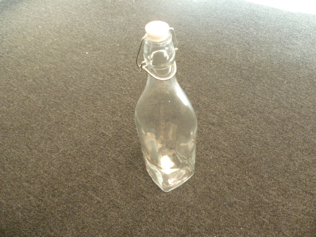 BOUTEILLE EN VERRE NON COLORE, DONT LE CORPS EST CARRE, MUNIE D'UN BOUCHON A ETRIER, D'UNE CONTENANCE DE 1 LITRE.  

DIMENSION 32 X 8 X 8 CM