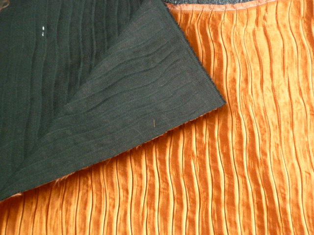 ETOFFE  CONTRECOLLEE, DE COULEUR CARAMEL, ASPECT SATINE ET PLISSE, SUR UN SUPPORT TISSU NOIR (POLYESTER). L'ETOFFE, ARMURE SATIN, EST EN FILAMENTS NON TEXTURES DE POLYESTER, EN FILS DE DIVERSES COULEURS.