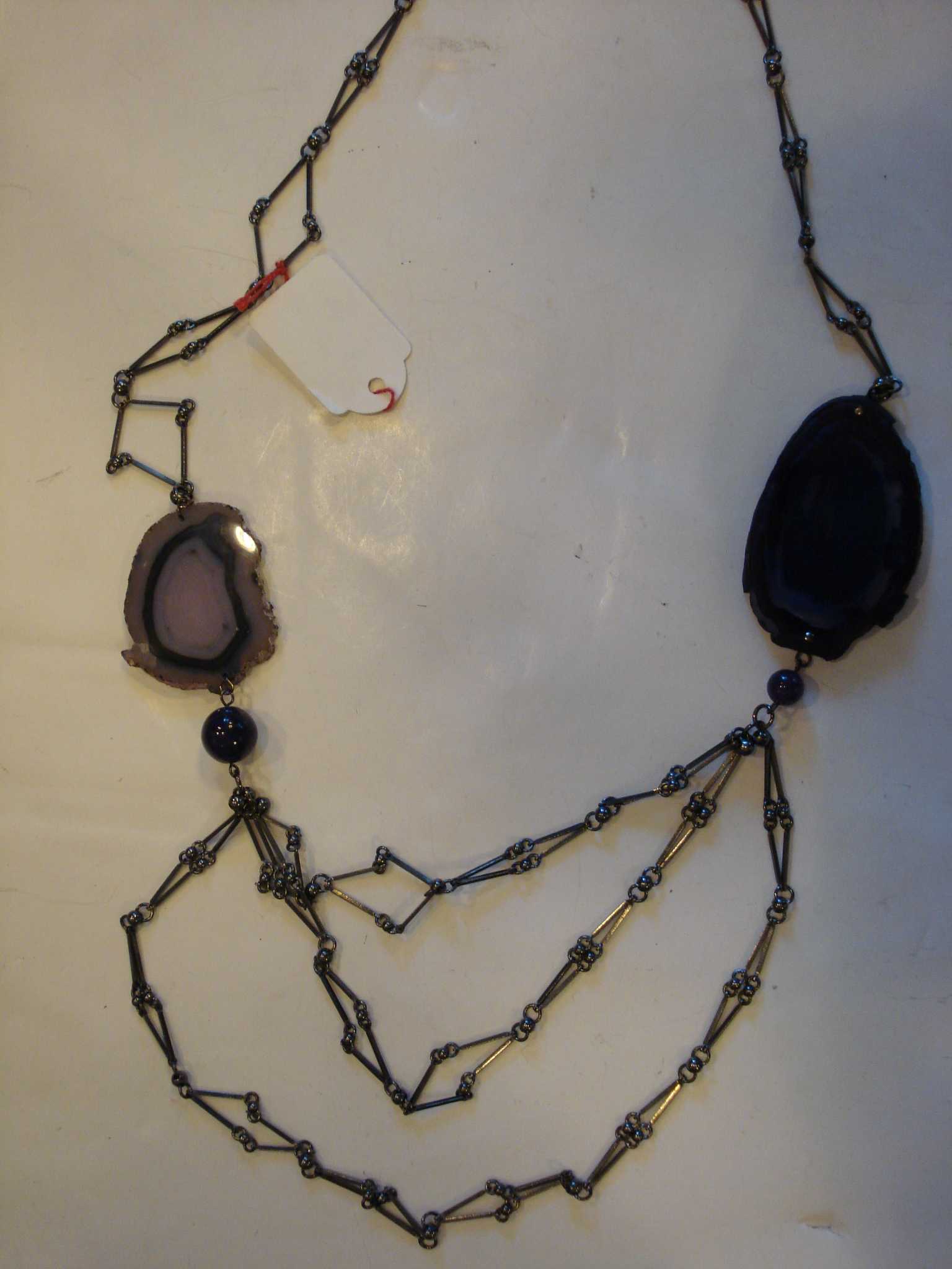 COLLIER COMPOSE DE PLUSIEURS RANGEES DE METAL ET DE PERLES DE VERRE, ET DE DEUX TRANCHES D'AGATE SITUEES L'UNE ET L'AUTRE DE CHAQUE COTE DU COLLIER.