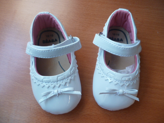 CHAUSSURE POUR BEBE, GENRE BALLERINE, AVEC UN DESSUS EN MATIERE PLASTIQUE COUVRANT PARTIELLEMENT LE DESSUS DU PIED, AVEC UNE BRIDE FERMANT PAR BANDE VELCRO AU NIVEAU DE LA CHEVILLE, AVEC UNE DOUBLURE ET UNE SEMELLE EXTERIEURE EN MATIERE TEXTILE, AVEC UNE SEMELLE INTERIEURE EN CUIR, AVEC UN PETIT NOEUD BLANC DECORATIF SUR LE DESSUS.