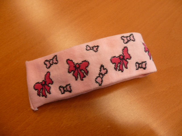 ACCESSOIRE DU VETEMENT, POUR ENFANTS, EN ETOFFE DE BONNETERIE DE FIBRES SYNTHETIQUES, SOUS LA FORME D'UN BANDEAU SERRE-TETE D'UNE LARGEUR DE 5  CM ENVIRON, AVEC DES MOTIFS DECORATIFS REPRESENTANT DES NOEUDS, DESTINE AU MAINTIEN DES CHEVEUX.