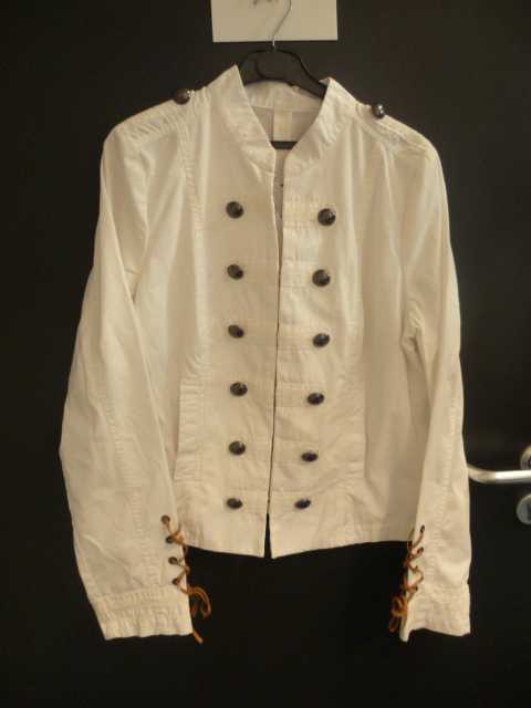 VETEMENT POUR FEMME, GENRE VESTE, EN TISSU DE COTON (100% COTON), DESTINE A COUVRIR LA PARTIE SUPERIEURE DU CORPS, DESCENDANT JUSTE AU DESSOUS DE LA TAILLE, AVEC UN COL OFFICIER, SE FERMANT  PAR DES AGRAFES, AVEC DES MANCHES LONGUES POURVUES A LEURS EXTREMITES D’UN POIGNET AVEC OURLET, AVEC A MI-BRAS HUIT OEILLETS PAR LESQUELS PASSENT UN LACET, AVEC UNE OUVERTURE COMPLETE SUR LE DEVANT AVEC DE CHAQUE COTE 6 BOUTONS EN METAL SERVANT DE DECORATION, AVEC UN MEME BOUTON SUR CHAQUE EPAULE, AVEC UNE POCHE DE CHAQUE COTE AU NIVEAU DE LA TAILLE, SANS DOUBLURE, AVEC DANS LE DOS A PARTIR DE LA TAILLE UN PLI CREUX, AVEC PLUSIEURS PANNEAUX FRONTAUX  ET  DORSAUX.