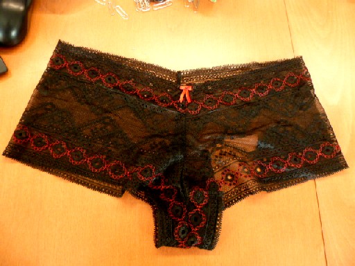 SLIP POUR FEMME, GENRE BOXER, CONFECTIONNE EN DENTELLE RACHEL BRODEE, COMPOSEE DE 94% DE POLYAMIDE ET 6% D'ELASTHANE, DE COLORIS NOIR AVEC DES BRODERIES DE COULEUR ROUGE, COMPORTANT UN FOND DOUBLE ET UN PEIT NOEUD SUR LE DEVANT.