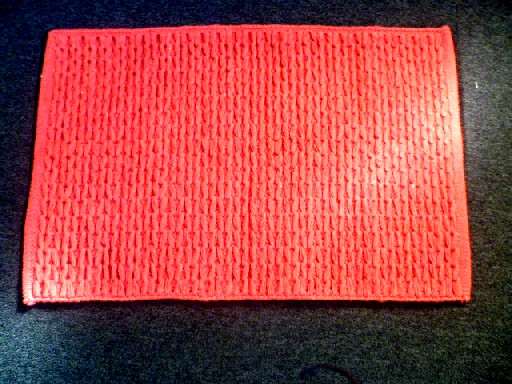 TAPIS DE BAIN, CONFECTIONNE EN TISSU 100% COTON, ASPECT TRICOT, DE FORME RECTANGULAIRE 76 CM X 50 CM, DE COULEUR UNIE ROUGE BRIQUE, NON TOUFFETE, NI FLOQUE, ET SANS VELOURS.