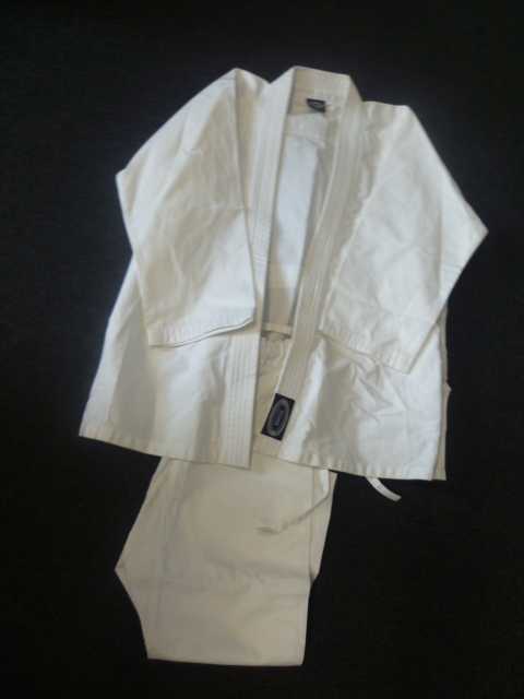 ENSEMBLE POUR ENFANT, EN TISSU DE COTON (100% COTON) COMPRENANT : - UN VETEMENT DESTINÉ A RECOUVRIR LA PARTIE SUPÉRIEURE DU CORPS, GENRE VESTE, AVEC DES MANCHES LONGUES, UNE OUVERTURE TOTALE SUR LE POURTOUR DE LAQUELLE EST COUSU UN LARGE BIAIS, AVEC UN RENFORT AU NIVEAU DE LA POITRINE DE CHAQUE COTE POUR LA PRISE DU KIMONO, AVEC UNE FENTE DE CHAQUE COTÉ PARTANT DE LA BASE D'UNE LONGUEUR DE 16 CM, AVEC UNE ÉTIQUETTE COUSUE REPRÉSENTANT LA MARQUE SUR LE BAS DU BIAIS ET UNE ÉTIQUETTE AU DOS AU NIVEAU DE L'ENCOLURE. LES MANCHES ET LA BASE SONT OURLÉES. - UN PANTALON, SANS OUVERTURE, DONT LA TAILLE EST ÉLASTIQUÉE, ET POUVUE D'UN CORDON A NOUER SUR LE DEVANT - UNE CEINTURE DANS LE MÊME TISSU de 106 CM, AVEC DES SURPIQUAGES