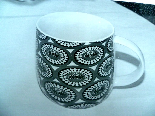 MUG, EN PORCELAINE "NEW BONE CHINA", DONT LA FACE INTERIEURE ET L'ANSE SONT DE COULEUR BLANCHE, ET LA FACE EXTERIEURE RECOUVERTE DE MOTIFS.