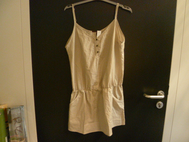 VETEMENT LEGER, GENRE NUISETTE DESTINE A RECOUVRIR LA PARTIE SUPERIEURE DU CORPS EN TISSU DE COTON D'UNE LONGUEUR DE 64 CM, DESCENDANT JUSQU'A MI-CUISSE ET POSSEDANT : 
- UN HAUT GENRE BUSTIER AVEC FERMETURE A BOUTONS SUR LE DEVANT
- DES BRETELLES  
- UN ELASTIQUE A LA TAILLE  
- DEUX POCHES EXTERIEURES PLAQUEES MUNIES D'UN LISERE BLANC 
- UN OURLET À LA BASE.