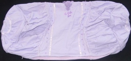A WOVEN BOLSTER SHAPED CUSHION COVER MEASURING 61 CMS. X 30 CMS. APPRO
X.  WITH A PARTIAL OPENING WITH A ZIP FASTENER.  WITH RUCHED PANELS.
WITH RIBBON, BEAD AND SILK FLOWER DECORATION.  WITH PIPING.  100% LINE
N.