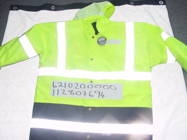 A WOVEN HIGH VISIBILITY OVERCOAT FOR MEN. CONSTRUCTED FROM A FABRIC TH
AT HAS A PU COATING THAT IS CONSIDERED VISIBLY TO THE NAKED EYE. DESIG
NED TO COVER THE UPPER PART OF THE BODY FROM THE SHOULDERS TO MID THIG
H. WITH A COMPLETE FRONT OPENING FASTENED WITH A ZIP AND LEFT OVER RIG
HT PRESS-STUD FLAP.  WITH A COLLAR THAT HAS A CONCEALED HOOD.  WITH LO
NG SLEEVES.  WITH TWO POCKETS ON THE LOWER FRONT OF THE GARMENT. WITH
 APPLIED REFLECTIVE STRIPS ON THE SLEEVES AND BODY OF THE GARMENT. LIN
ED AND PADDED. 100% POLYESTER.
