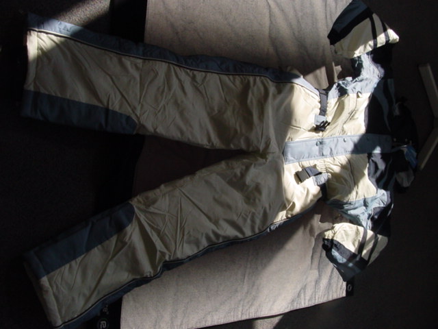 AN ALL IN ONE SKI OVERALL DESIGNED TO COVER THE UPPER AND LOWER PART OF THE BODY. WITH LONG SLEEVES WITH ELASTICATED CUFFS. WITH OPENING TO BELOW THE WAIST. FASTENED WITH A ZIP AND PROTECTIVE FLAP FASTENED WITH PRESS STUDS LEFT OVER RIGHT. WITH CONCEALED HOOD IN THE COLLAR WITH DRAWSTRING FASTENING. WITH ELASTICATED WAIST WITH DETACHABLE BELT AND BELT LOOPS. HEMMED AT LEG ENDS, WITH A ZIPPED VENT AND VELCRO TABS WHICH TIGHTEN THE LEG ENDS. WITH AN INNER ELASTICATED  CUFF. WITH CONCEALED POCKETS AT HIP LEVEL FASTENED WITH ZIPS.WITH THERMAL PADDED LINING. 100% POLYESTER. PACKAGED ON A HANGER IN A GARMENT BAG WHICH HAS BEEN CLASSIFIED SEPARATELY. CROSS REFERENCE 112919189