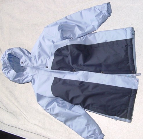 A WOVEN PADDED COAT FOR GIRLS.  DESIGNED TO COVER THE BODY FROM THE SHOULDER TO THE BELOW MID-THIGH.  WITH A VISIBLE P.U. COATING ON THE INNER SURFACE.  LINED.  WITH A COMPLETE OPENING  WITH A ZIP FASTENER.  WITH A RIGHT OVER LEFT STORM FLAP  WHICH HAS A POPPER FASTENING.  WITH AN ATTACHED ELASTICATED HOOD.  WITH LONG SLEEVES WHICH HAVE AN ELASTICATED AND VELCRO TIGHTENING AT THE CUFF.  WITH A VERTICAL ZIPPED POCKET EACH SIDE ON LOWER FRONT.  WITH CENTRE BACK ELASTICATION APPROX. 23 CMS. FROM BASE.  WITH DRAWSTRING TIGHTENING AT BASE.  100% POLYESTER.