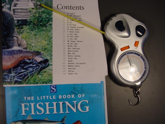 MULTI FUNCTION FISHING TOOL, COMPRISING OF A WIRE CUTTER, WEIGHT SCALE AND TAPE MEASURE. IT IS HAND HELD. IT IS SUPPLIED WITH AN A TO Z  OF FISHING BOOK.  IT IS CONSIDERED TO BE A  COMPLIMENTARY SET PUT UP FOR RETAIL SALE. THE MULTI TOOL IS  MADE OF SILVER COLOURED PLASTIC WITH ORANGE AND BLUE FUNCTION BUTTONS.