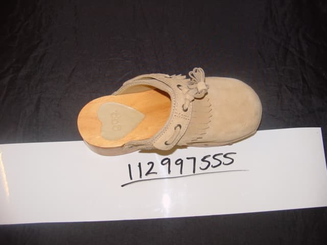 CHILDS CLOG STYLE SHOE. UPPERS OF LEATHER (SUEDE). PLATFORM OF WOOD. THIN  OUTER SOLES OF PLASTIC/RUBBER. NO INNER SOLE. TASSELS ON VAMP. DECORATIVE HEART SHAPED STUDS AROUND BASE.  NOT COVERING THE ANKLE. INSOLE LENGTH LESS THAN 24CMS.