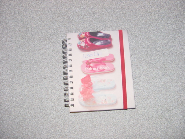 HARDBACK ADDRESS BOOK. SPIRAL BOUNDED. MEASURING 12cm LONG BY 9.5cm WIDE (APPROXIMATELY). SPACES FOR NAME, ADDRESS, HOME, WORK AND CELL PHONE NUMBERS AND E-MAIL ADDRESS. ELASTIC FASTENER TO KEEP THE BOOK CLOSED. PACKAGED TOGETHER  IN SPECIFICALLY DESIGNED PACKAGING FOR RETAIL SALE. AS A SET WITH METAL SHOE CHARM AND A BOOK THAT HAS BEEN CLASSIFIED SEPARATELY.