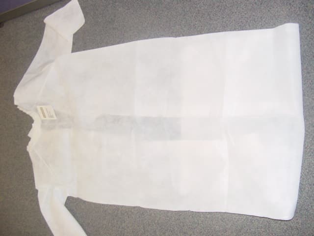 SHROUD MADE FROM A NON WOVEN FABRIC USED TO DRESS A DECEASED BODY. INTENDED COVER THE WHOLE OF THE BODY. WITH A ROUND CLOSE FITTING RUCHE NECKLINE. WITH A COMPLETE OPENING AT THE BACK FASTENED WITH TIES. WITH LONG SLEEVES WITH TAPE FASTENING AT THE WRISTS.