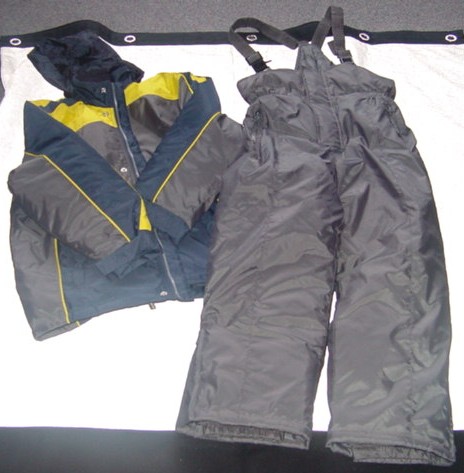 A WOVEN SKI SUIT FOR BOYS.  COMPRISING OF AN ANORAK AND SALOPETTES. PADDED AND LINED. ANORAK HAS A COMPLETE OPENING WITH A ZIP FASTENER AND A LEFT OVER RIGHT POPPER CLOSURE.  WITH A FOLD AWAY ELASTICATED HOOD WITH VELCRO FASTENING. WITH A COLLAR. WITH LONG SLEEVES, WITH VELCRO TIGHTENING AT SLEEVE ENDS.  WITH AN INNER ELASTICATED CUFF.  WITH A ZIPPED POCKET EACH SIDE ON LOWER FRONT AND AN INSIDE BREAST POCKET. HEMMED AT BASE.  IN THREE CONTRASTING COLOURED FABRICS WITH PIPING. MATCHING PLAIN DYED PADDED SALOPETTES. WITH A ZIP FLY WITH A LEFT OVER RIGHT VELCRO CLOSURE.  ELASTICATED AT WAIST.  WITH  ADJUSTABLE ELASTICATED BRACES.  WITH ZIP POCKETS. HEMMED AT LEG ENDS.  WITH A ZIPPED VENT AND  AN INNER ELASTICATED  CUFF.  100% POLYAMID. WITH A COATING WHICH IS NOT DEEMED TO BE VISIBLE TO THE NAKED EYE.