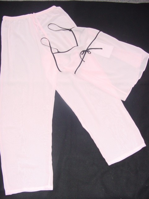 WOVEN PYJAMAS FOR WOMEN. CONSISTING OF UPPER GARMENT REACHING DOWN TO BELOW WAIST. CAMISOLE STYLE TOP WITH V NECK. WITH SATIN FINISH CONTRASTING BINDING AT THE NECKLINE, AROUND THE ARMHOLES AND FORMING ADJUSTABLE SHOULDER STRAP. WITH FURTHER BINDING UNDER THE BUST LINE, WITH TIE-UP BOW.  HEMMED AT THE BASE. WITH  LOOSE FITTING ANKLE LENGTH TROUSERS AS LOWER GARMENT. ENVELOPING EACH LEG SEPARATELY. WITH ELASTIC AT THE WAIST WITH FUNCTIONAL TIES. WITHOUT OPENING. HEMMED AT THE LEG ENDS. BOTH ITEMS ARE MADE OF SHEER FABRIC, OF 100 % POLYESTER.