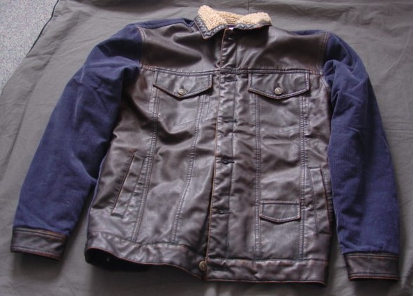A WOVEN CORDUROY JACKET FOR MEN. DESIGNED TO COVER THE UPPER PART OF THE BODY FROM THE SHOULDERS TO THE HIP. PADDED.  WITH A FLEECE LINING.  WITH A COMPLETE OPENING WITH A LEFT OVER RIGHT BUTTON FASTENING. WITH A ROUND NECK. WITH AN ATTACHED COLLAR.  WITH LONG SLEEVES WITH A BUTTONED CUFF.  WITH VARIOUS POCKETS.  WITH A TAB AND BUTTON DECORATION EACH SIDE AT BASE (NOT A TIGHTENING). THE FRONT OF THE GARMENT, THE BASE AND CUFFS ARE MADE FROM A SYNTHETIC PVC LEATHER LOOK MATERIAL.  THERE ARE ALSO STRIPS OF THE SAME MATERIAL ON THE BACK AND SLEEVES.   THE MAJORITY FABRIC IS A COTTON CORDUROY.