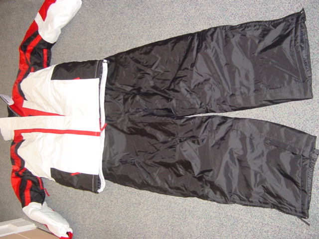 A WOVEN SKI SUIT FOR MEN. COMPRISING OF AN ANORAK AND TROUSERS.  THE ANORAK HAS A COMPLETE FRONT OPENING WITH A ZIP AND LEFT OVER RIGHT VELCRO FASTENING. WITH A COLLAR THAT HAS A CONCEALED HOOD.  WITH LONG SLEEVES WITH ZIPPED VENTS UNDER EACH ARM. WITH ELASTICATED AND VELCRO CUFFS. WITH VARIOUS ZIPPED POCKETS ON THE FRONT OF THE GARMENT. WITH AN INNER POWDER SKIRT. WITH A DRAWSTRING TOGGLE TIGHTENING AT THE BASE OF THE GARMENT. IN THREE CONTRASTING COLOURS. THE TROUSERS ARE MATCHING PLAIN DYED. ENVELOPING EACH LEG SEPARATELY. WITH MATCHING ELASTICATED BRACES WITH ZIP FLY AND LEFT OVER RIGHT PRESS-STUD AND PROTECTIVE FLAP. WITH A BELT. WITH SIDE POCKETS. HEMMED AT LEG ENDS WITH A ZIPPED VENT AND AN INNER ELASTICATED CUFF. PADDED AND LINED 100% POLYAMIDE.