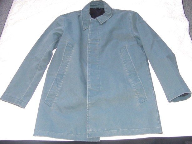 A WOVEN JACKET FOR MEN.  DESIGNED TO COVER THE BODY FROM THE SHOULDERS TO MID-THIGH.  LINED.  WITH A COMPLETE OPENING WITH A LEFT OVER RIGHT BUTTON FASTENING.  WITH A FLAP OVER BUTTONS.  WITH A ROUND NECK WITH COLLAR.  WITH LONG SLEEVES.  WITH A DIAGONAL POCKET EACH SIDE ON LOWER FRONT WITH ANOTHER POCKET DIRECTLY ABOVE. WITH A CENTRE BACK VENT.  HEMMED AT SLEEVE ENDS AND AT BASE. 100% COTTON.