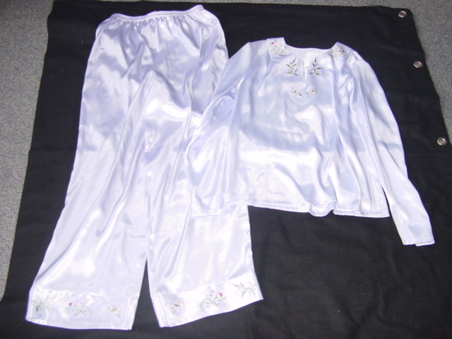 WOVEN PYJAMAS FOR UNISEX. SATIN LOOK, WITH LOOSE FITTING UPPER GARMENT.  ROUND NECK WITH CUT OUT V-SHAPED NOTCH AT FRONT, WITH NARROW STRAP OF FABRIC JOINING THE TWO EDGES OF THE NOTCH AT THE TOP. LONG SLEEVES WITH CUT OUT V-SHAPED NOTCH AT SLEEVE ENDS.  HEMMED AT BASE OF GARMENT AND AT SLEEVE ENDS.  WITH EMBROIDERED DECORATION AT FRONT OF NECKLINE.  PACKED WITH TROUSERS OF SAME FABRIC.  ELASTICATED WAIST WITHOUT OPENING.  WITH MATCHING EMBROIDERED,  APPLIED BAND AT BASE OF LEGS.  100% POLYESTER
